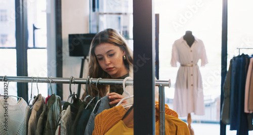 Just browsing. Shot of a young woman browsing through clothes in a boutique.