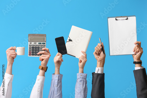Business people with cup of coffee, calculator, mobile phone, folder and clipboard on blue background