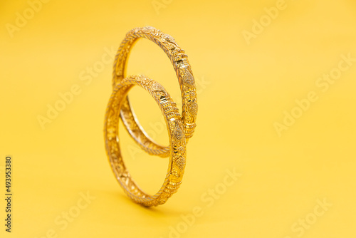 gold jewelry bracelet for women over on yellow background