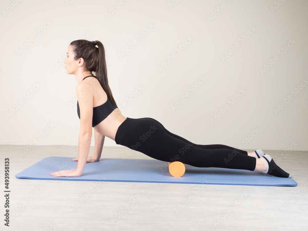 European girl is engaged in Fitness. cool down after workout. self-massage of leg and thigh muscles on a massage roller. European girl is engaged in Fitness. cool down after workout. self-massage of leg and thigh muscles on a massage roller.