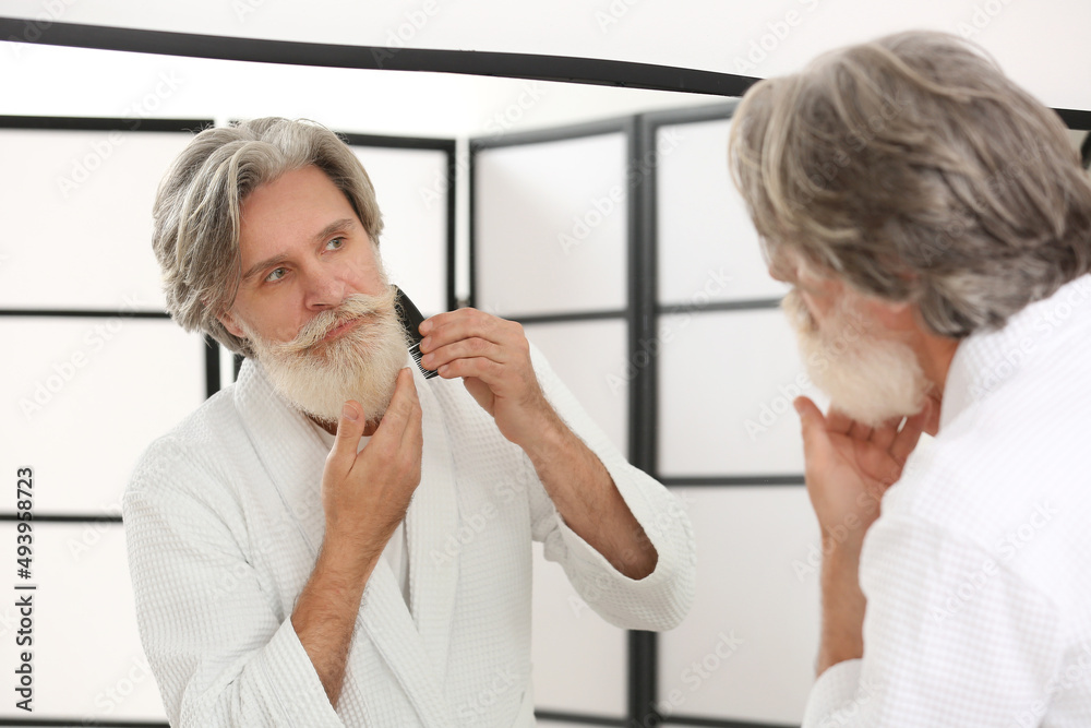 Mature man taking care of his beard and mustache in bathroom Mature man taking care of his beard and mustache in bathroom