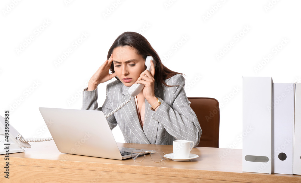 Stressed secretary with laptop talking by phone at table on white background Stressed secretary with laptop talking by phone at table on white background