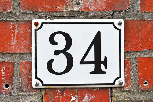 Sign of a street number 34 on a red brick wall photo