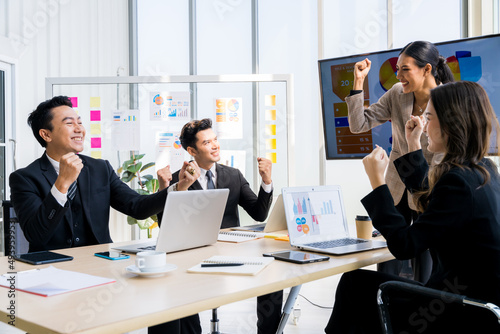 A group of young businessmen in suits, Asians, are determined and excited about their work. and encourage the team members by raising their hands happily