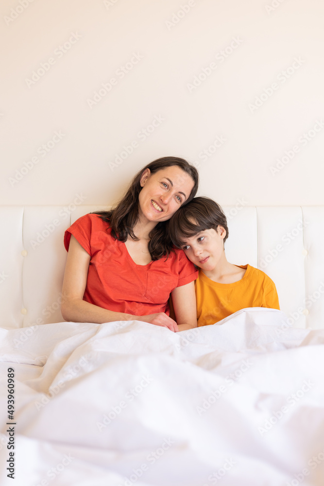 A child with mom sit on the bed, a woman hugs her son A child with mom sit on the bed, a woman hugs her son