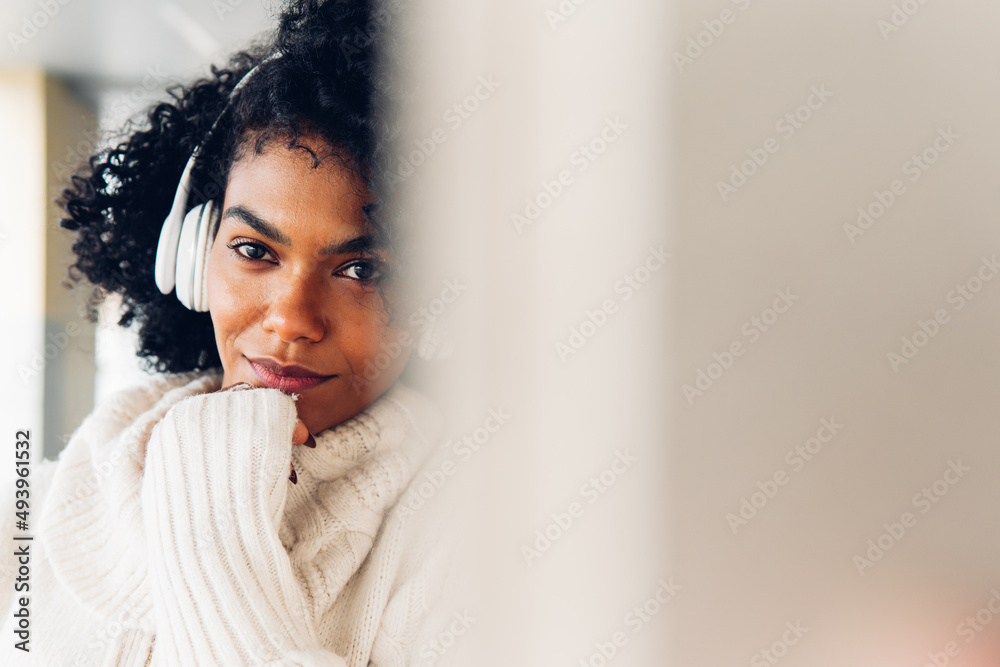 Portrait of a young woman with afro hair leaning against a white wall, listening to music with headphones. Serene, enjoying, concept of music, life and urban style. copy and writing space. Portrait of a young woman with afro hair leaning against a white wall, listening to music with headphones. Serene, enjoying, concept of music, life and urban style. copy and writing space.