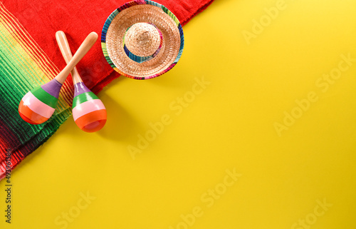 Cinco de Mayo holiday background made from maracas, mexican blanket stripes or poncho serape and hat on yellow background. photo