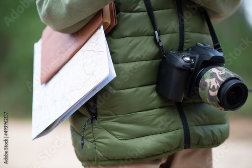 Close-up of modern photo camera and map. Person with digital camera with big lens and map in folder. Technology, hobby concept
