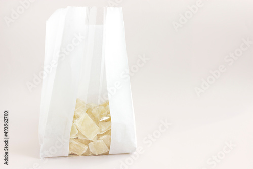 Healthy organic snack: dried (dehydrated)  Aloe Vera chunks in the white craft packaging bag  isolated on  white, light pink background, horizontal plane, copy space on the right. Tasty food.Superfood