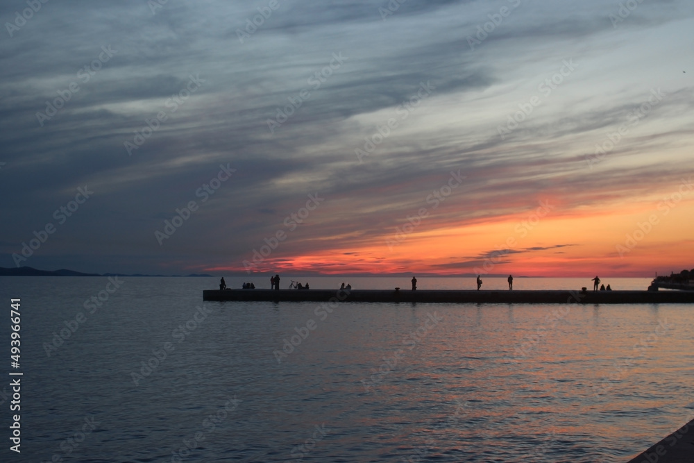 Sunset time in beach , people are fishing watching sunset , Colorful Sun Croatia Zadar Sunset time in beach , people are fishing watching sunset , Colorful Sun Croatia Zadar