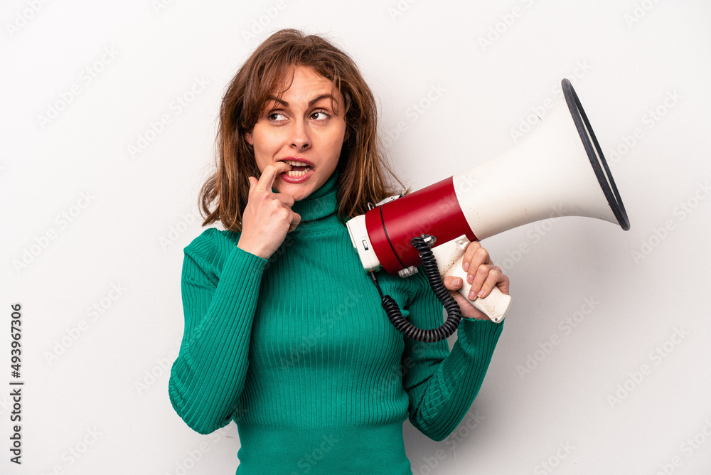 Young caucasian woman holding a megaphone isolated on white background relaxed thinking about something looking at a copy space. Young caucasian woman holding a megaphone isolated on white background relaxed thinking about something looking at a copy space.
