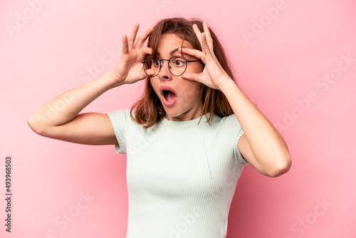 Young caucasian woman isolated on pink background keeping eyes opened to find a success opportunity.