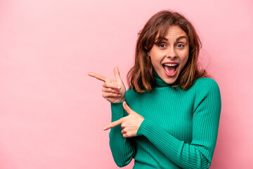 Young caucasian woman isolated on pink background excited pointing with forefingers away.