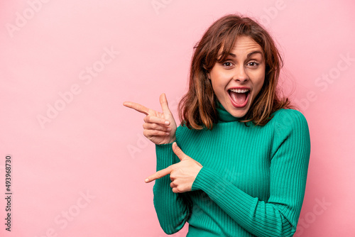 Young caucasian woman isolated on pink background excited pointing with forefingers away.