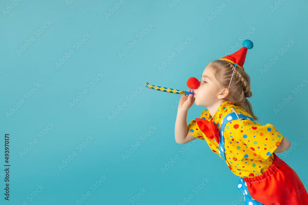 Funny kid clown against blue background. Happy child playing with festive decor. Birthday and 1 April Fool's day concept - obrazy, fototapety, plakaty 