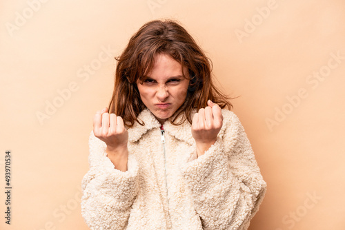 Young caucasian woman isolated on beige background upset screaming with tense hands. © Asier