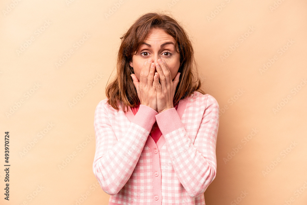 Young caucasian woman isolated on beige background shocked, covering mouth with hands, anxious to discover something new. Young caucasian woman isolated on beige background shocked, covering mouth with hands, anxious to discover something new.