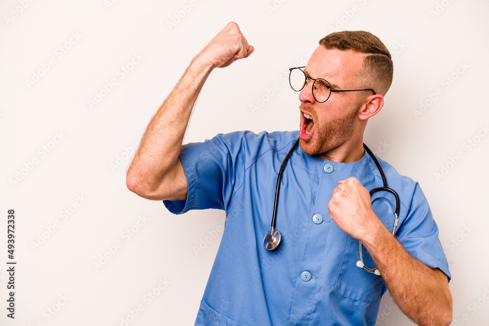 Young caucasian nurse man isolated on white background raising fist after a victory, winner concept. Young caucasian nurse man isolated on white background raising fist after a victory, winner concept.