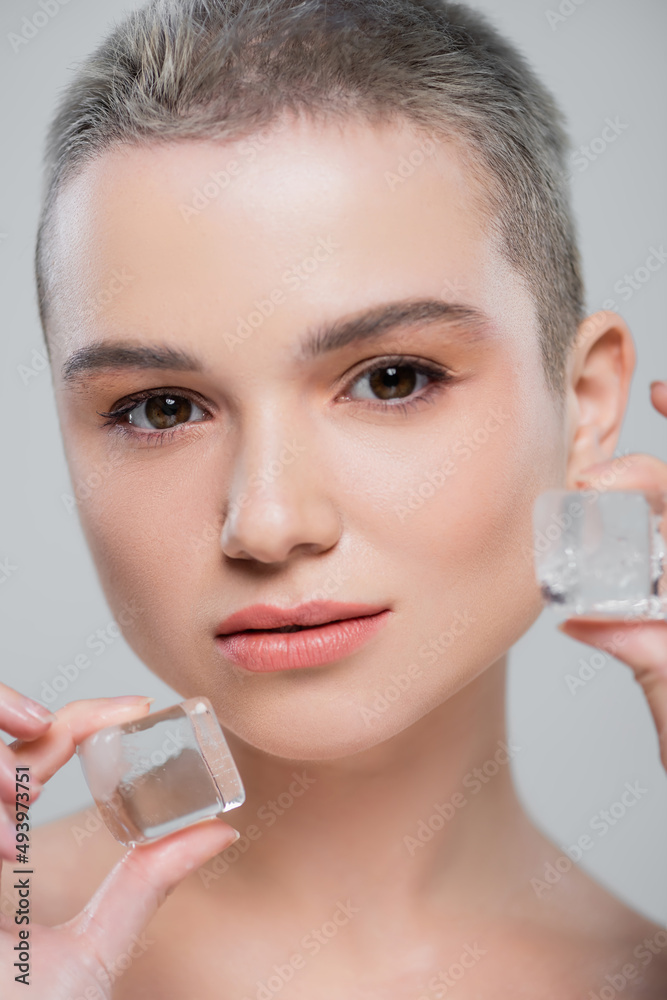 portrait of young woman with natural makeup near ice cubes isolated on grey. portrait of young woman with natural makeup near ice cubes isolated on grey.