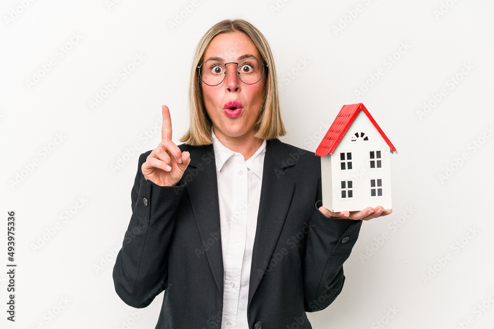 Young business caucasian woman holding a toy house isolated on white background having some great idea, concept of creativity. Young business caucasian woman holding a toy house isolated on white background having some great idea, concept of creativity.