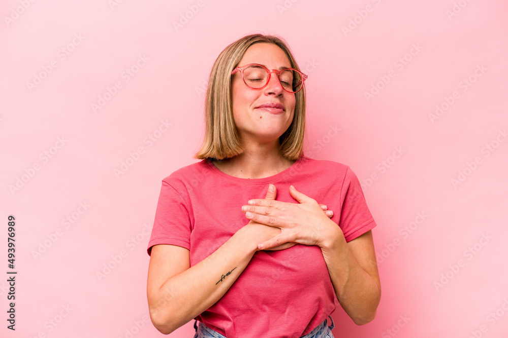Young caucasian woman isolated on pink background has friendly expression, pressing palm to chest. Love concept. Young caucasian woman isolated on pink background has friendly expression, pressing palm to chest. Love concept.
