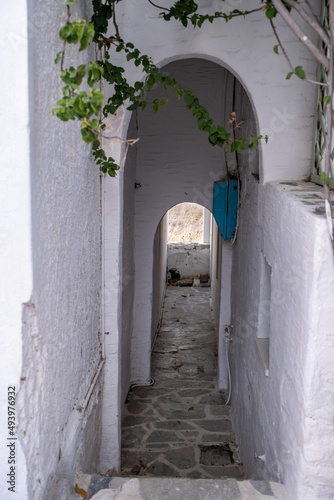 Greek Island, Cyclades. Stair, narrow cobblestone street, arch wall covers alley. Vertical