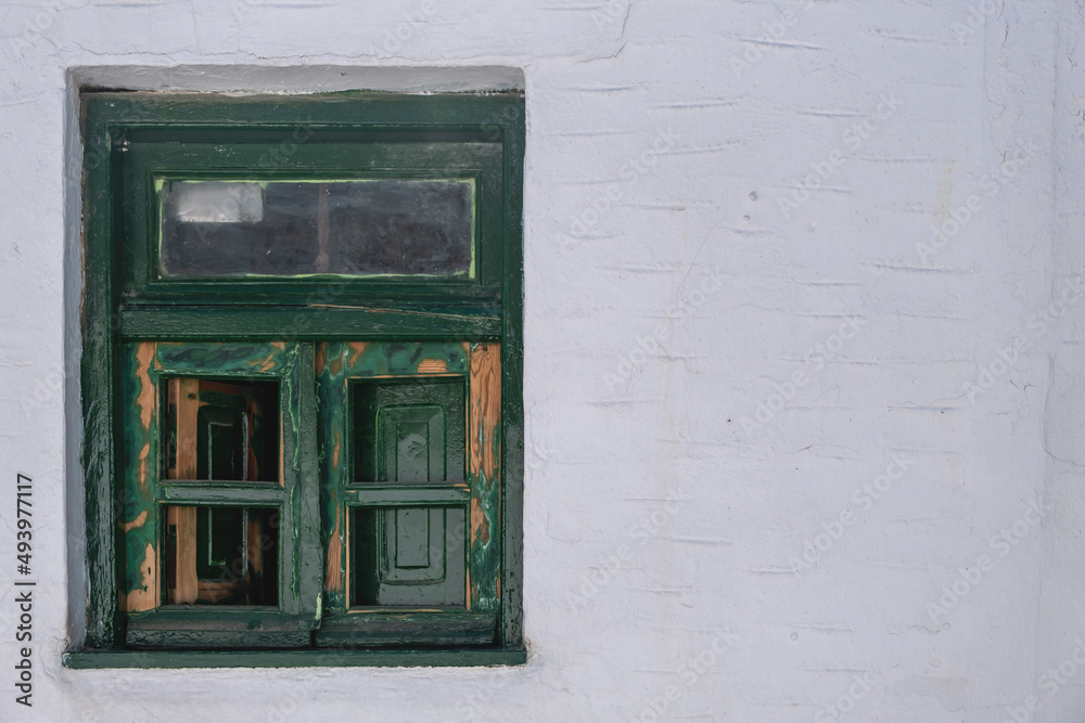 Greek Island, Greece. Wooden weathered vintage window, aged whitewashed stonewall background.