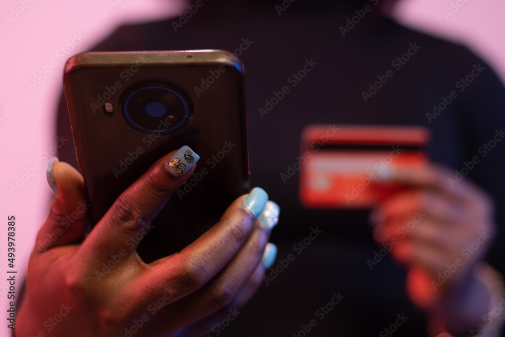 african woman using her phone and credit card