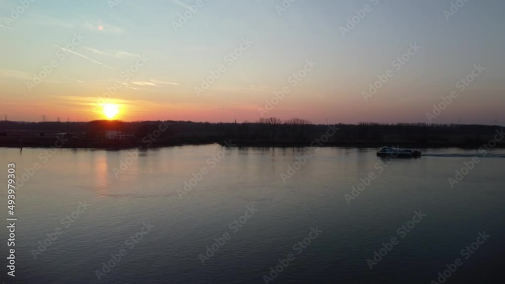 Passenger boat sailing on river Scheldt during golden sunset, aerial ascend view Passenger boat sailing on river Scheldt during golden sunset, aerial ascend view