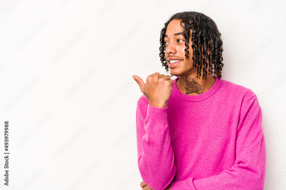 Young African American man isolated on white background points with thumb finger away, laughing and carefree. Young African American man isolated on white background points with thumb finger away, laughing and carefree.