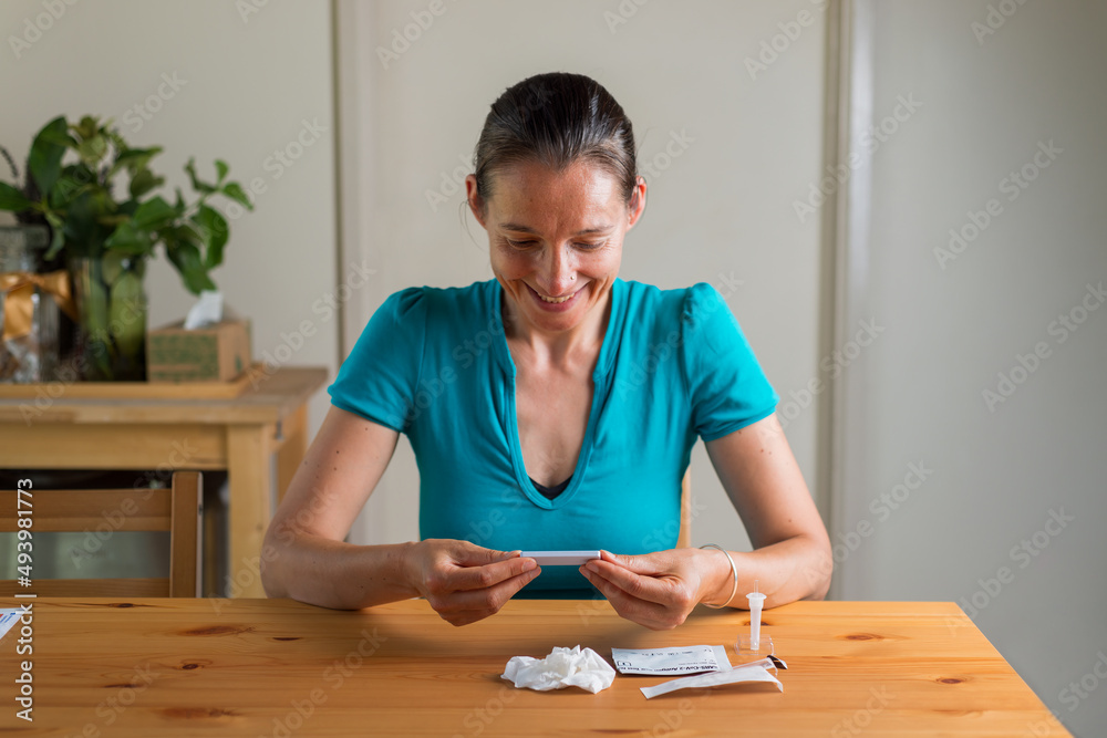 Happy smiling woman looking at negative Rapid antigen test results. Happy smiling woman looking at negative Rapid antigen test results.