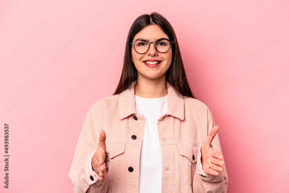 Young caucasian woman isolated on pink background holding something with both hands, product presentation. Young caucasian woman isolated on pink background holding something with both hands, product presentation.