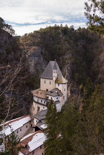 Aerial view of the Sanctuary of San Romedio surrounded by trees under a blue cloudy sky photo