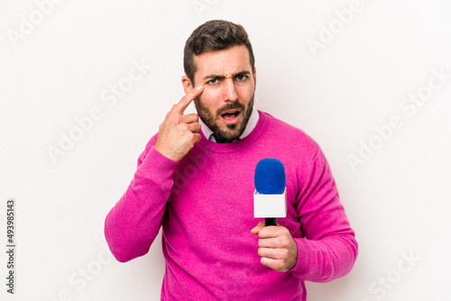 Young caucasian tv presenter man isolated on white background showing a disappointment gesture with forefinger. © Asier