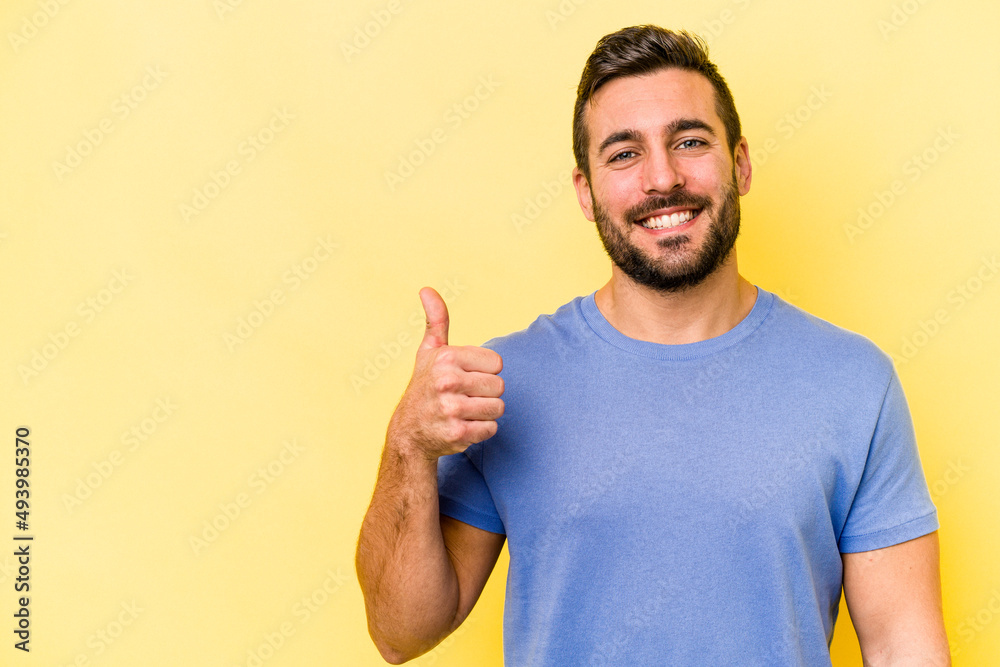 Young caucasian man isolated on yellow background smiling and raising thumb up Young caucasian man isolated on yellow background smiling and raising thumb up