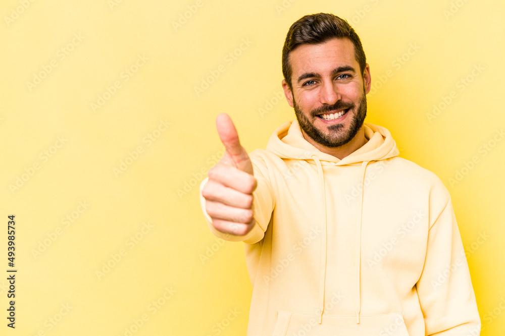 Young caucasian man isolated on yellow background smiling and raising thumb up Young caucasian man isolated on yellow background smiling and raising thumb up