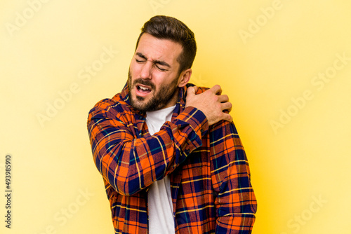 Young caucasian man isolated on yellow background having a shoulder pain.
