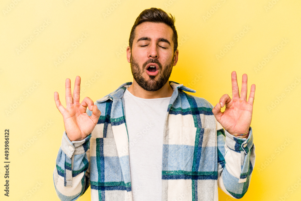 Young caucasian man isolated on yellow background relaxes after hard working day, she is performing yoga. Young caucasian man isolated on yellow background relaxes after hard working day, she is performing yoga.
