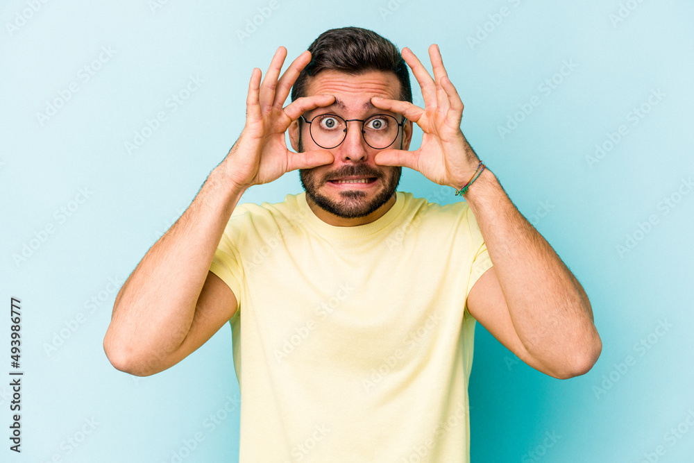 Young caucasian man isolated on blue background keeping eyes opened to find a success opportunity. Young caucasian man isolated on blue background keeping eyes opened to find a success opportunity.
