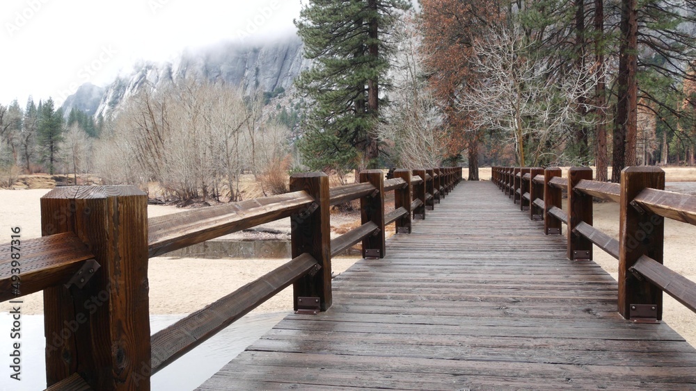 Wooden bridge or catwalk perspective in autumn pine tree forest, Yosemite valley landscape, California fall nature, USA. Hiking or trekking in wilderness, footbridge on boardwalk trail for ecotourism. Wooden bridge or catwalk perspective in autumn pine tree forest, Yosemite valley landscape, California fall nature, USA. Hiking or trekking in wilderness, footbridge on boardwalk trail for ecotourism.