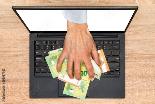 Fotografie Hand reaching out of laptop screen to steal money