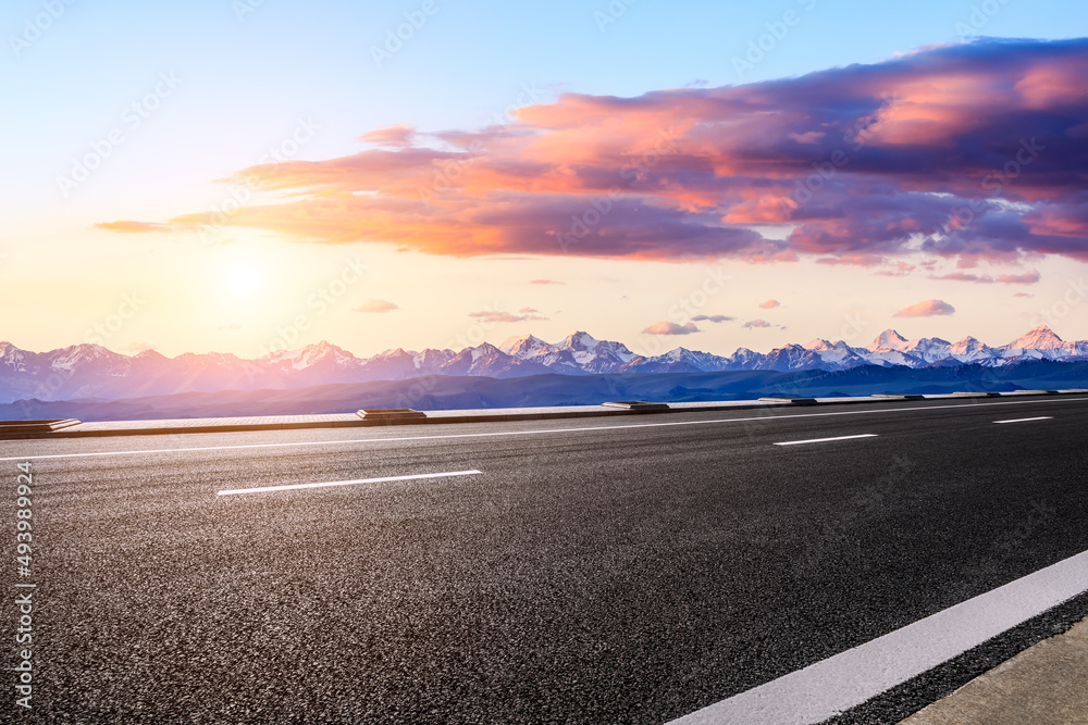 Fototapeta premium Asphalt road and snow mountains with beautiful clouds at sunrise