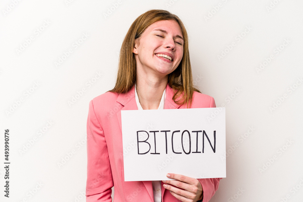 Young English business woman holding a bitcoin placard isolated on white background laughing and having fun. Young English business woman holding a bitcoin placard isolated on white background laughing and having fun.