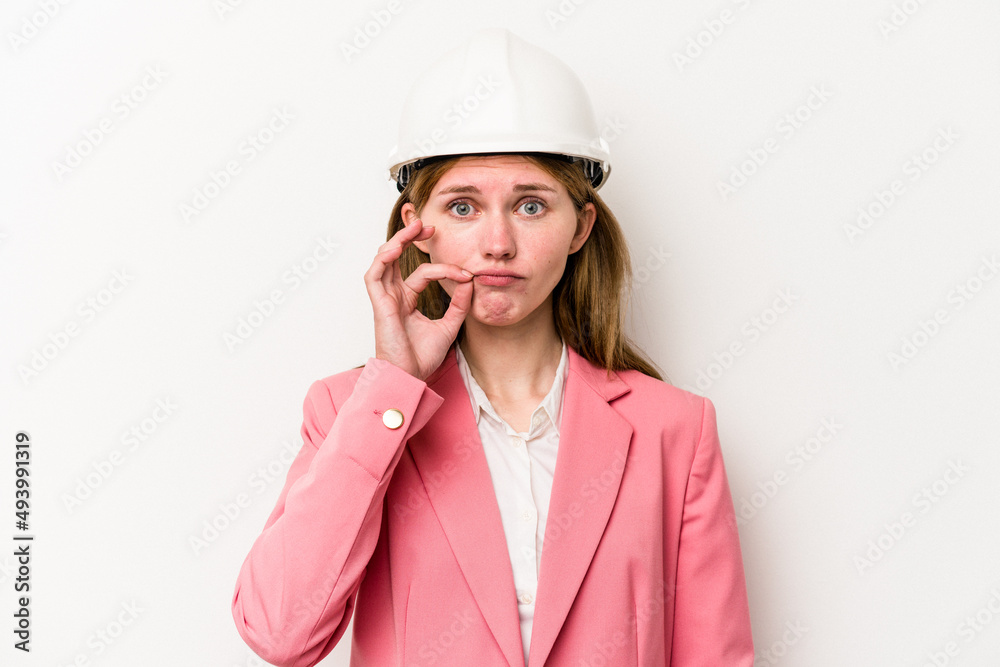 Young architect English woman with helmet isolated on white background with fingers on lips keeping a secret.