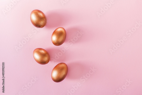 Set of Easter golden color eggs isolated on pastel pink background. Stylish trendy frame composition with gold chocolate egg. Flat lay, top view, place for text. Happy egg hunt for kids concept