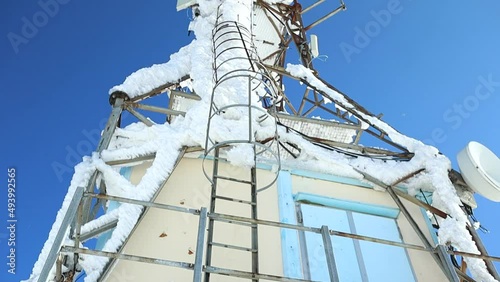 large antenna covered with snow and ice on top of the mountain, botto to top shot photo