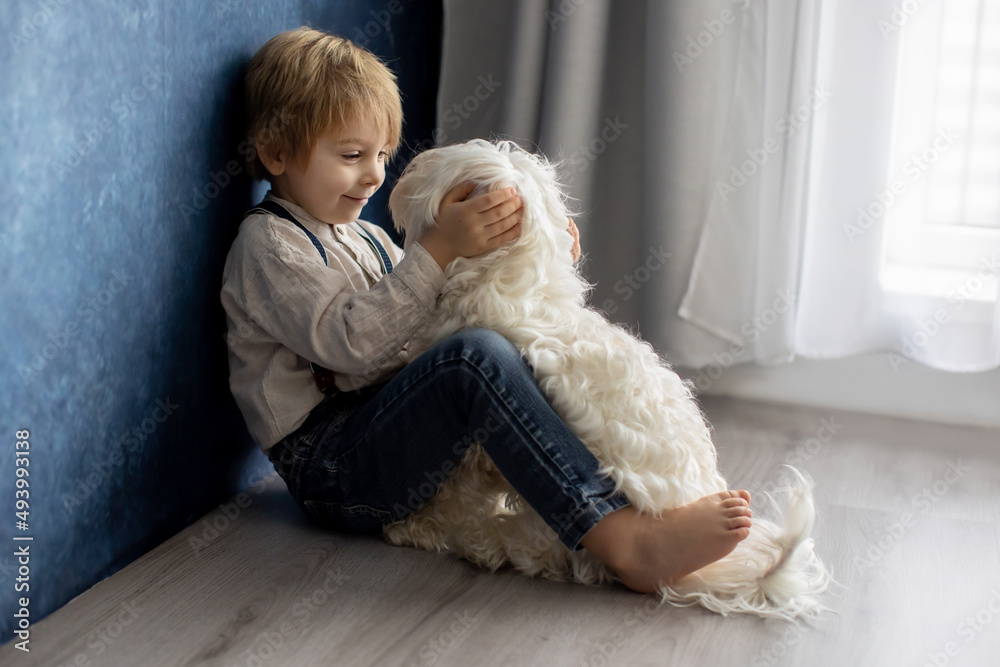 Cute blond preschool boy, sitting on the floor with pet dog, punished for mischief Cute blond preschool boy, sitting on the floor with pet dog, punished for mischief