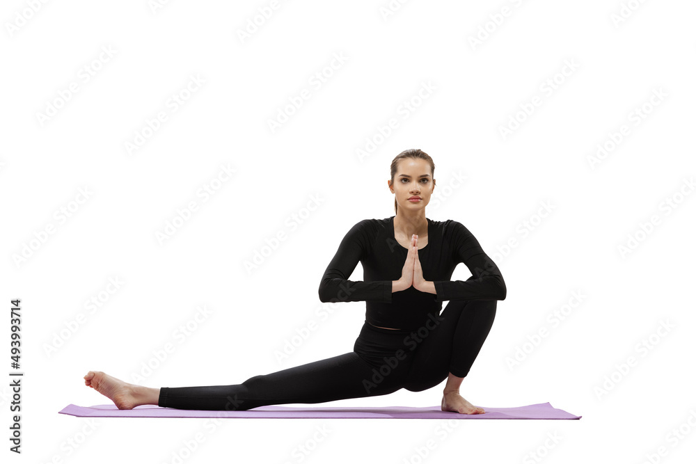 Portrait of young girl training, doing stretching and yoga exercises isolated over white studio background Portrait of young girl training, doing stretching and yoga exercises isolated over white studio background