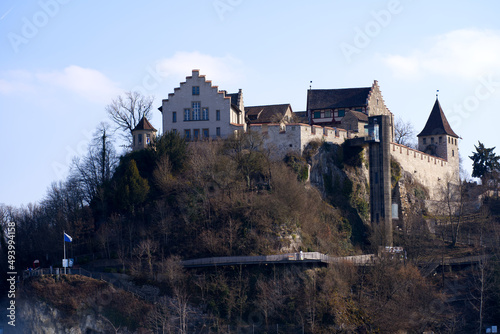 Famous Rhine Falls with rocks, splashing water and Laufen Castle on top of a hill on a sunny spring day, focus on background. Photo taken March 7th, 2022, Zurich, Switzerland.