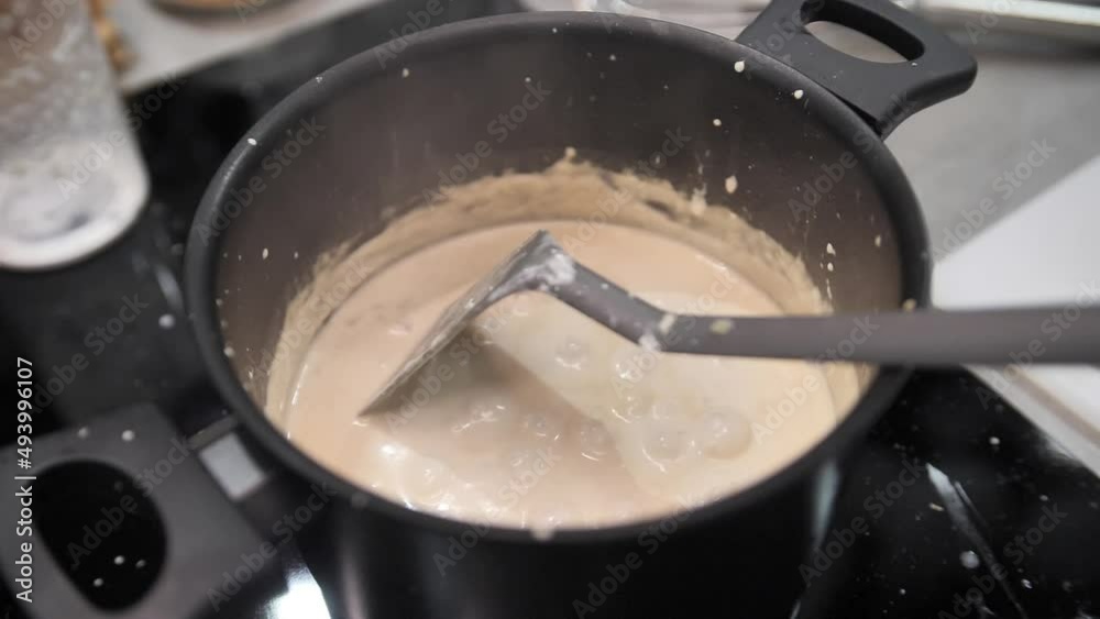 Close up of woman s hand stirring white cream in a pan at home. Close up of woman s hand stirring white cream in a pan at home.
